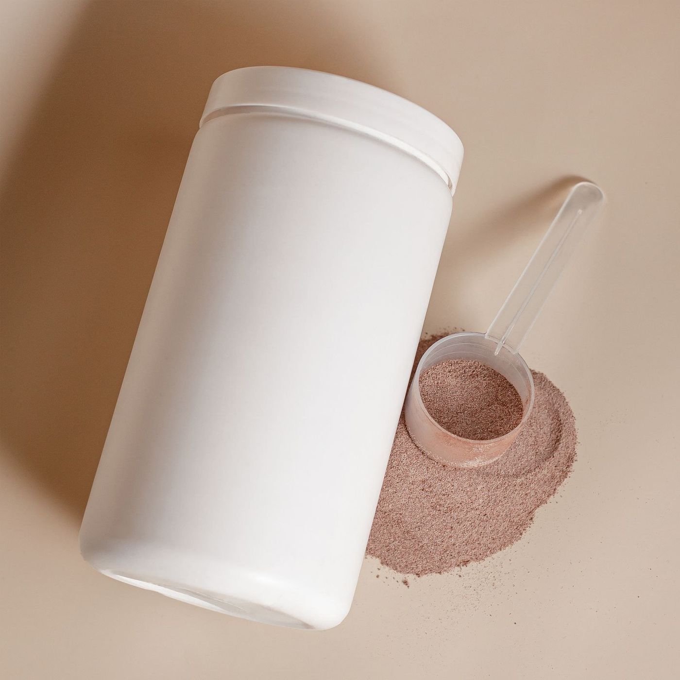 Pote branco sem rótulo e dosador com whey achocolatado, em estúdio de fundo bege