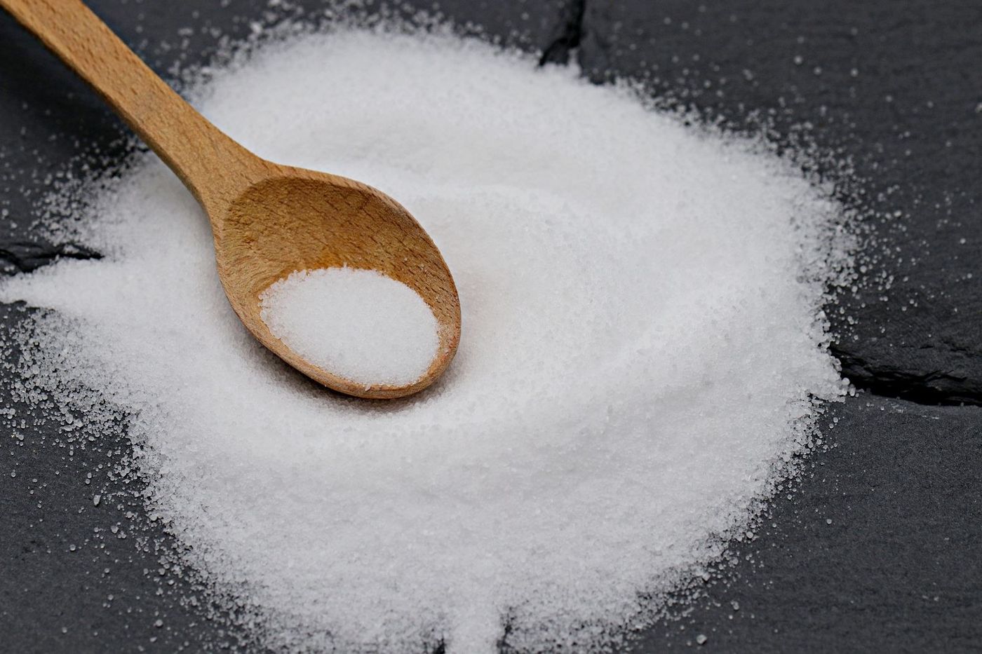 Colher de pau com pó branco sobre uma pedra escura